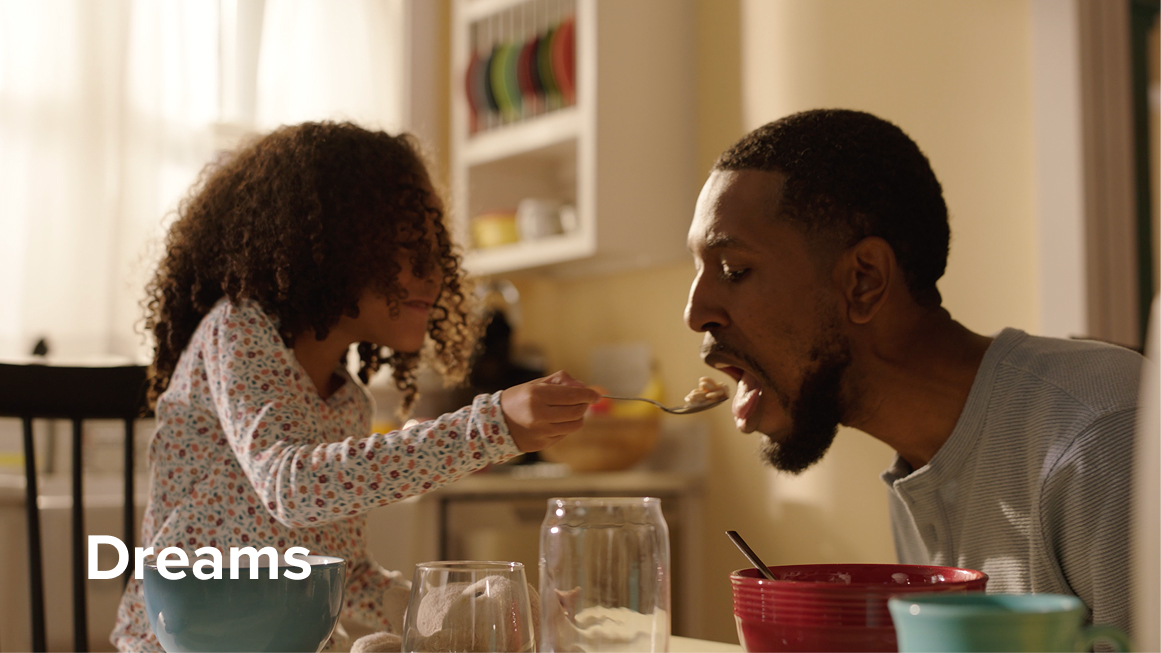 Daughter giving a bite of cereal to her dad